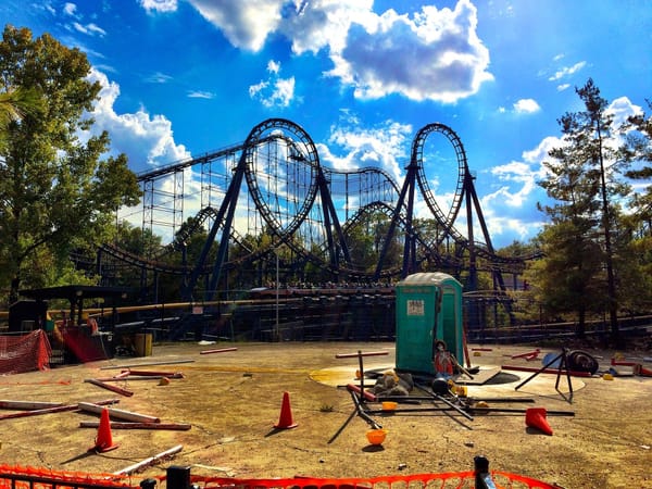 The Vortex roller coaster, featuring loops and corkscrews in the background of an empty and messy flat ride plot.